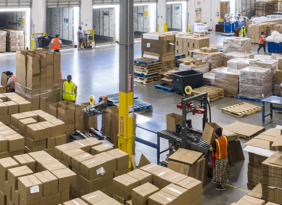Warehouse floor beside the dock: cases banded onto pallets, empty pallets stacked, staff working the line.