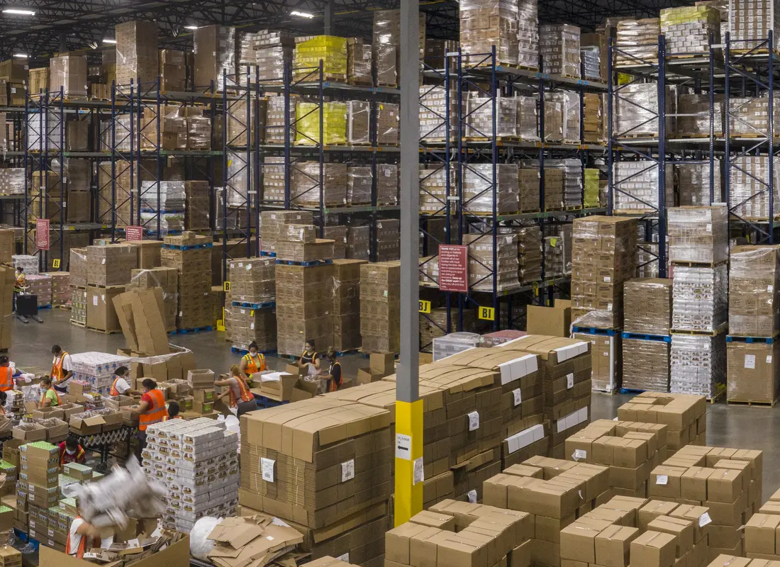 Reserve racking loaded with palletised cases beside a pack-out area.