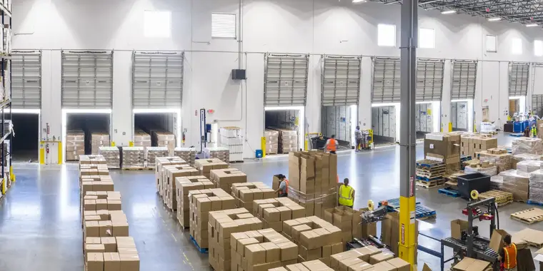 Dock doors of a distribution warehouse with rows of palletised cases staged for loading.