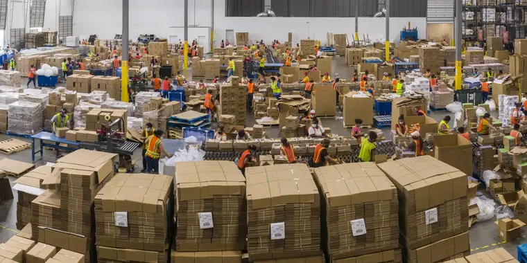 Pack-out floor of a distribution warehouse: pallets of cases being built, banded and labelled.