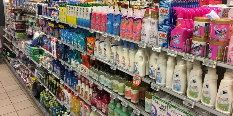 Supermarket cleaning aisle: laundry detergents, fabric softeners and surface cleaners in full facings under shelf-edge price labels.